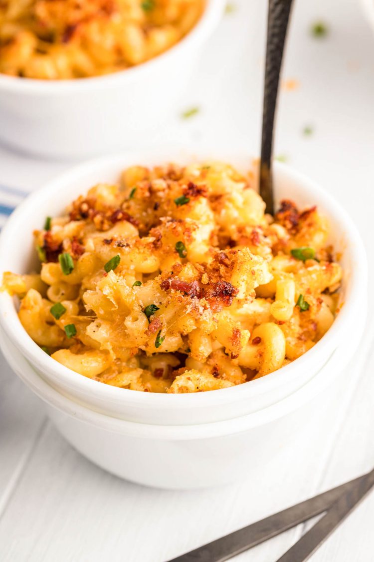 Close up photo of smoked mac and cheese in a white bowl with a fork in it.