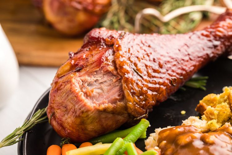 Close up photo of a turkey leg on a black plate for Thanksgiving dinner.