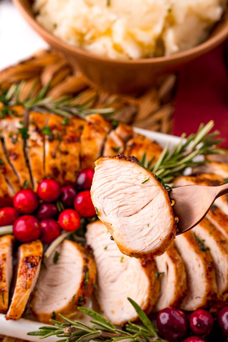 A close up photo of a slice of turkey tenderloin being held to the camera.