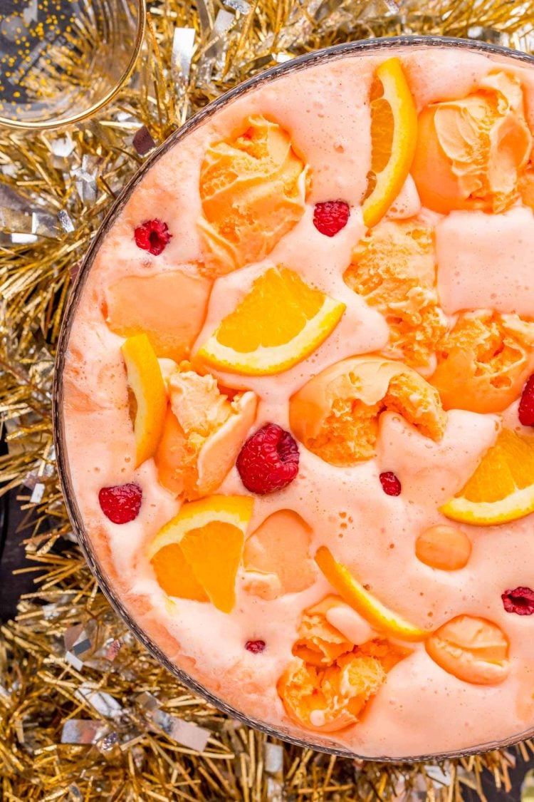 Overhead photo of a bowl of sherbet party punch with tinsel garland around the bottom of the bowl.