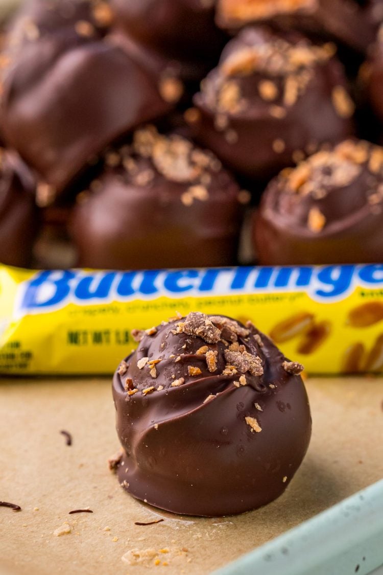 Butterfinger truffles on parchment paper with more truffles in the background.