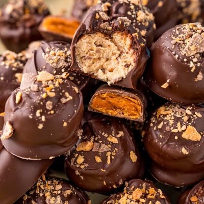 Close up photo of a pile of butterfinger peanut butter balls on a baking sheet.