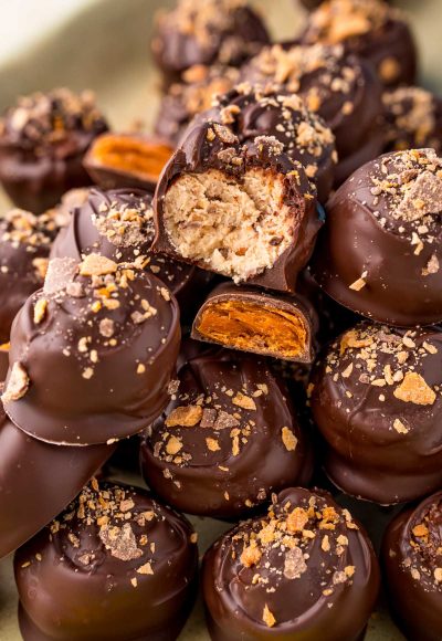 Close up photo of a pile of butterfinger peanut butter balls on a baking sheet.