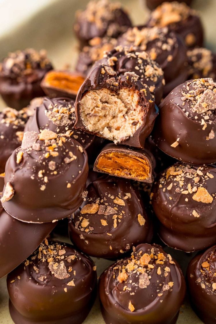 Close up photo of a pile of butterfinger peanut butter balls on a baking sheet.