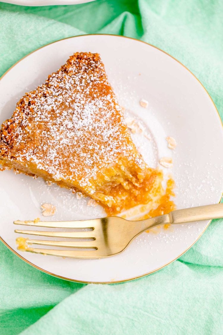 A slice of Crack Pie on a white plate on a green napkin with a fork.