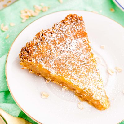 Close up photo of a slice of crack pie on a white plate on a green napkin.