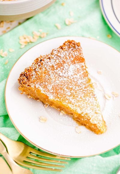 Close up photo of a slice of crack pie on a white plate on a green napkin.