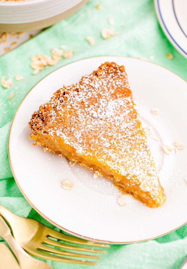 Close up photo of a slice of crack pie on a white plate on a green napkin.