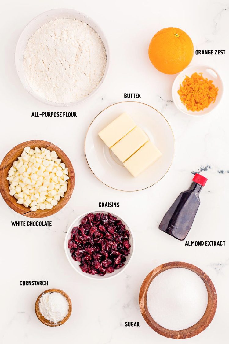 Overhead photo of ingredients prepped to make cranberry orange shortbread cookies on a white marble counter.