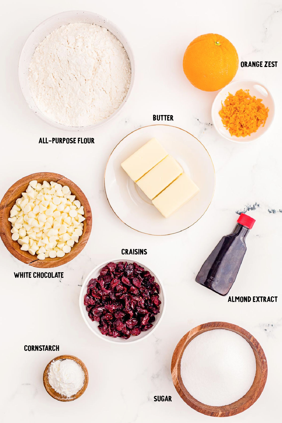 Overhead photo of ingredients prepped to make cranberry orange shortbread cookies on a white marble counter.
