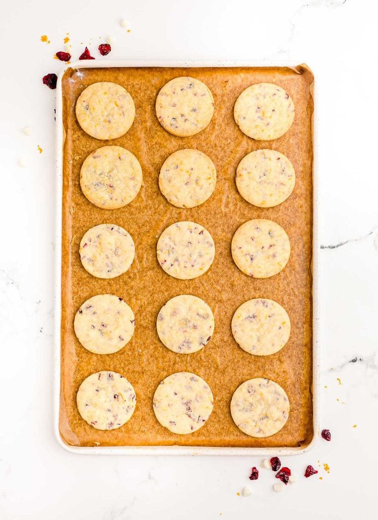 Cranberry orange cookies on a parchment lined baking sheet.