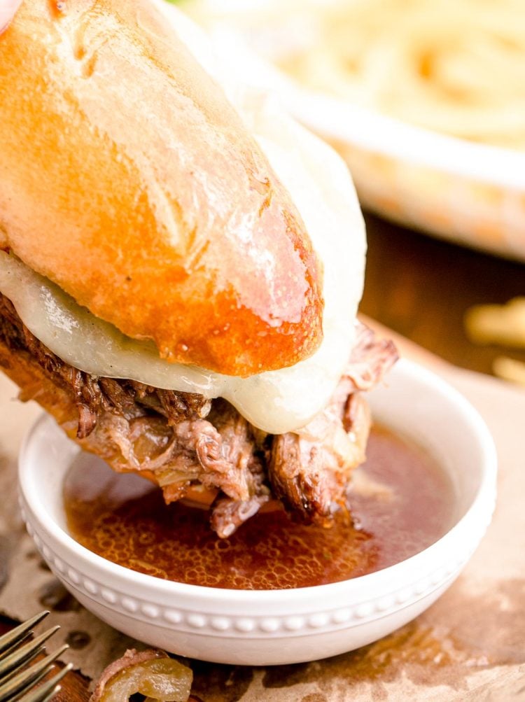 French Dip Sandwich being dipped in au jus.