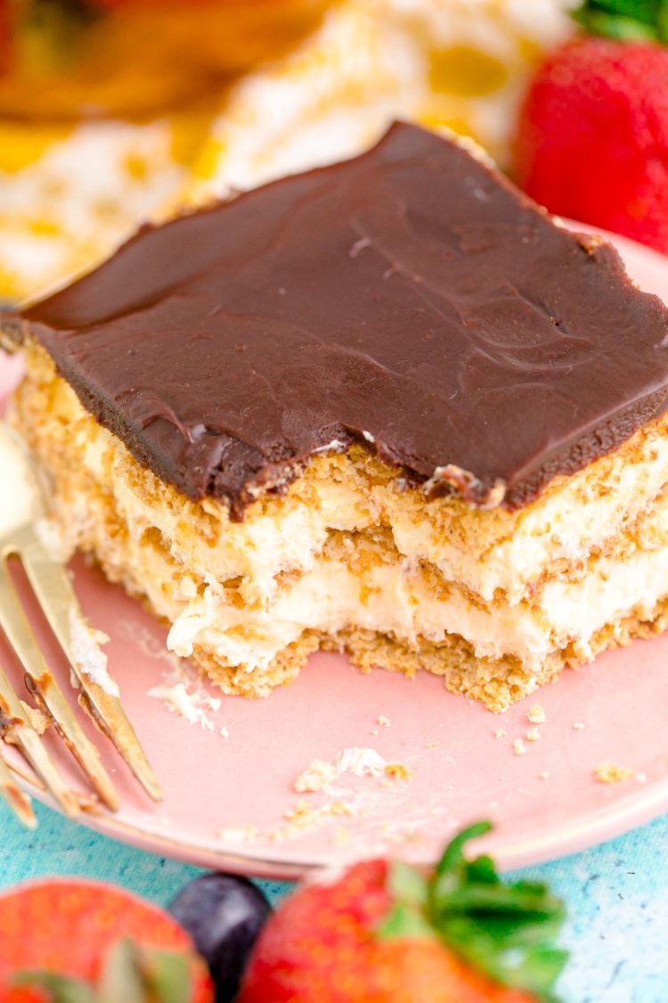 A slice of eclair icebox cake on a pink plate with a bite missing.