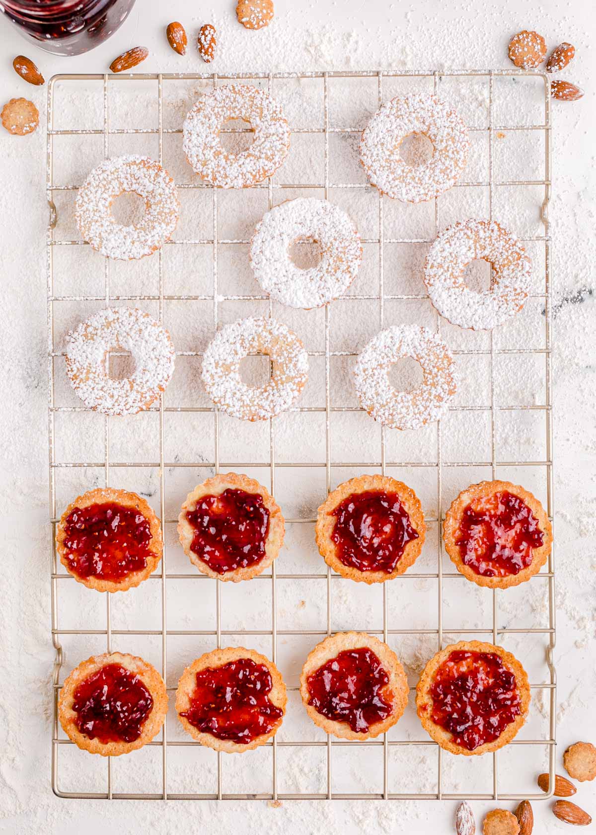 Linzer cookie halves being prepared on a wire rack.