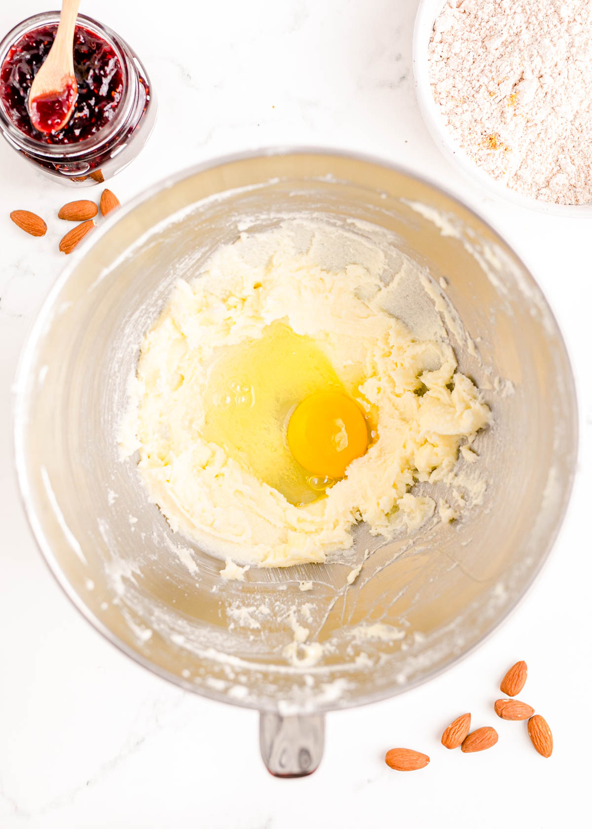 An egg added to a stand mixer bowl ready to be beaten into cookie dough.