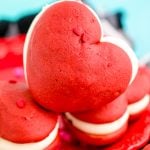 Close up photo of heart shaped red velvet whoopie pies on a red plate.