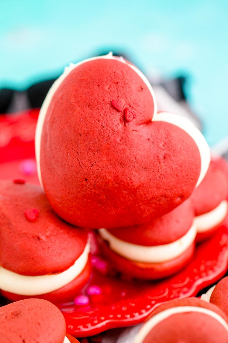 Close up photo of heart shaped red velvet whoopie pies on a red plate.