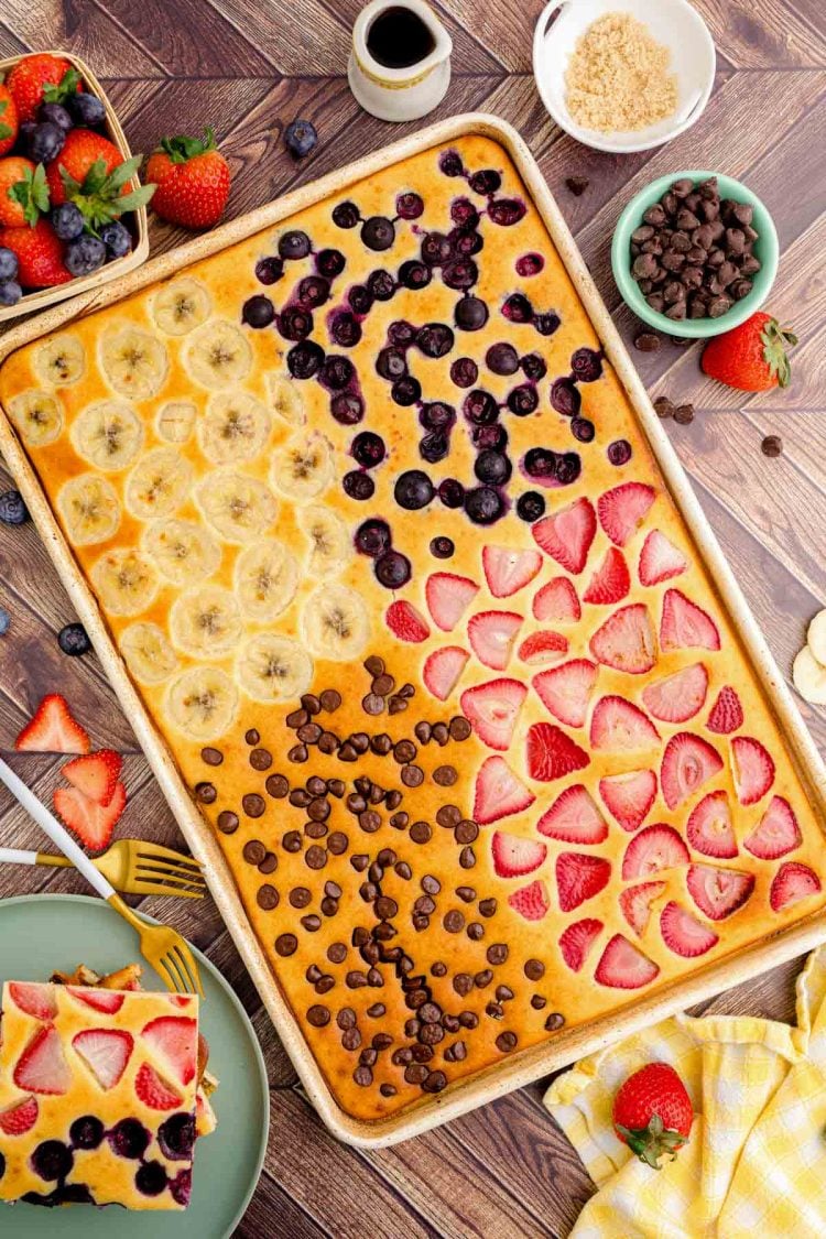 Overhead photo of sheet pan pancakes on a wooden table with 4 different flavors.