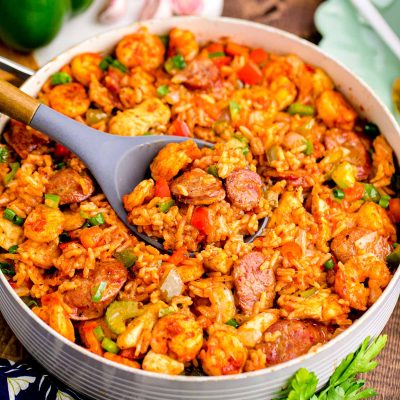 Close up photo of a pan with jambalaya in a pan with ingredients around it.