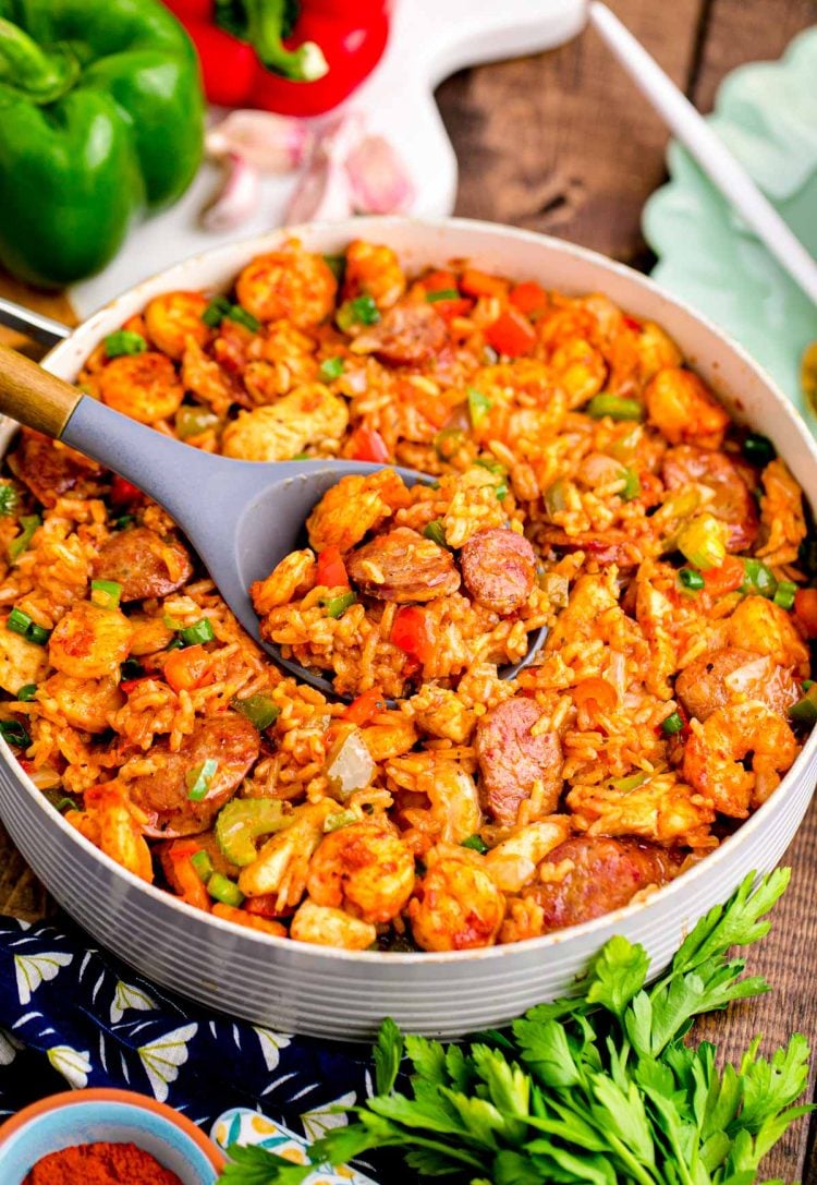 Close up photo of a pan with jambalaya in a pan with ingredients around it.
