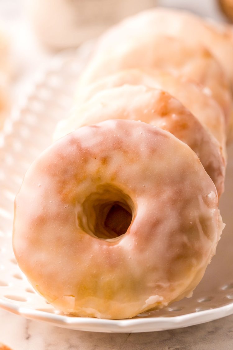 Glazed donuts on a white serving platter.