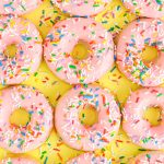 Overhead close up photo of pink frosted donuts covered in sprinkles for a birthday.