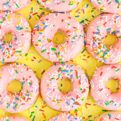 Overhead close up photo of pink frosted donuts covered in sprinkles for a birthday.