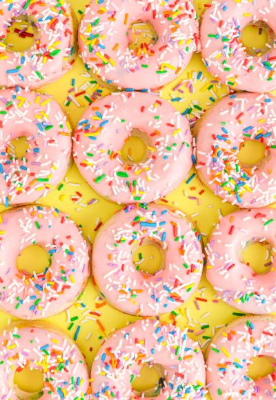 Overhead close up photo of pink frosted donuts covered in sprinkles for a birthday.