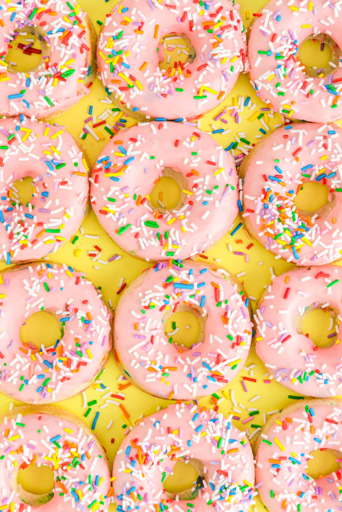Overhead close up photo of pink frosted donuts covered in sprinkles for a birthday.