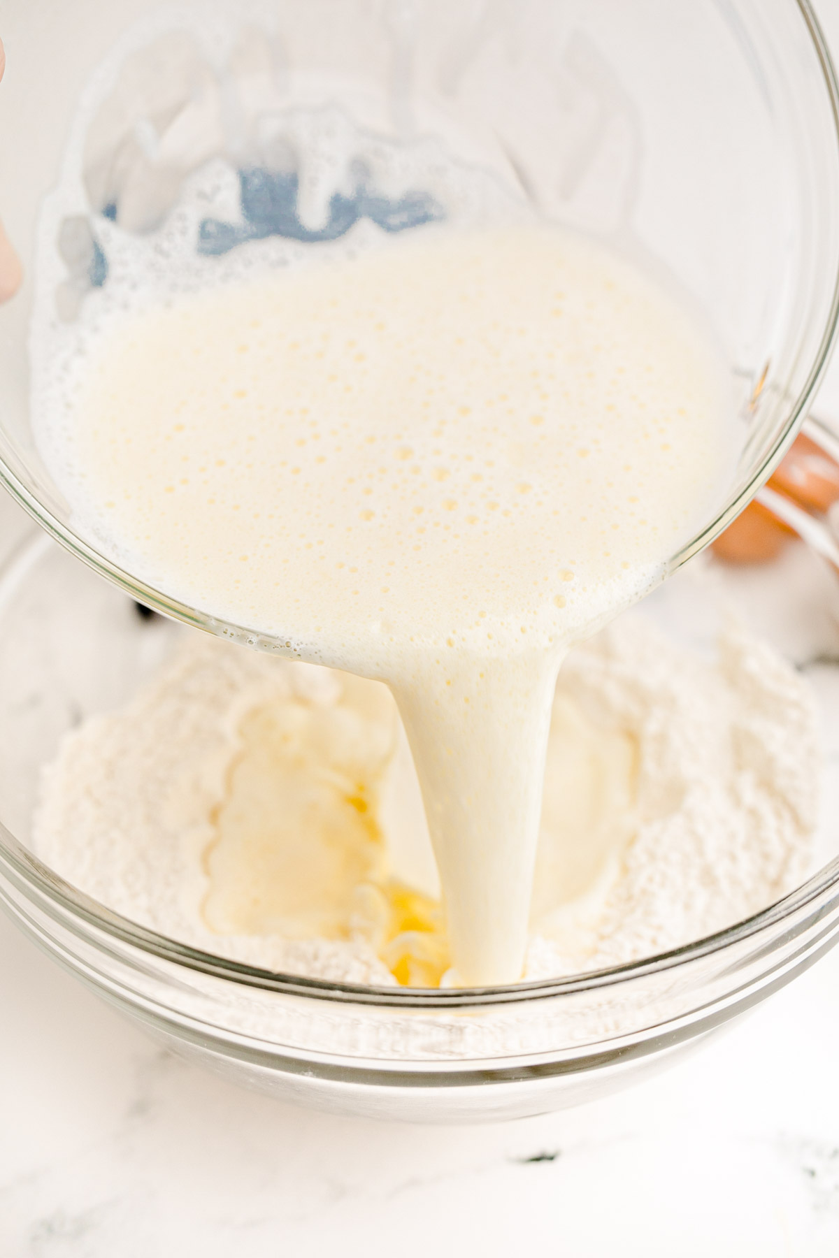 Egg and milk mixture being poured into dry ingredients to make blueberry pancakes.