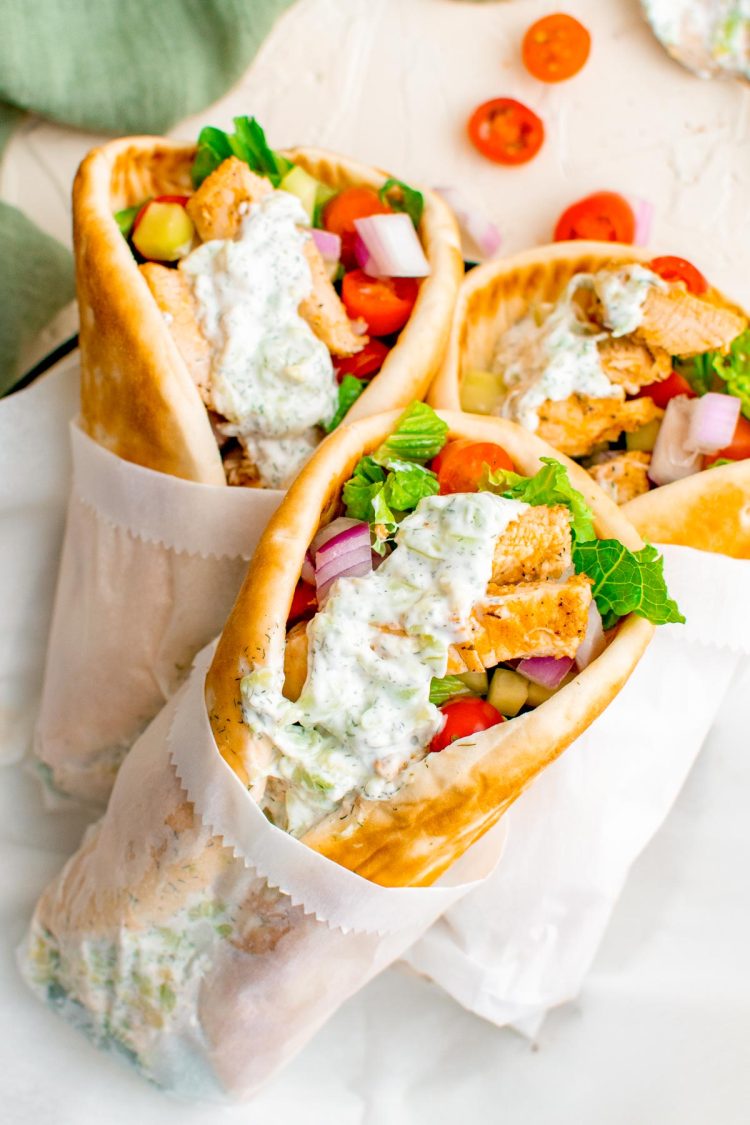 Three chicken gyros stacked up on a table.