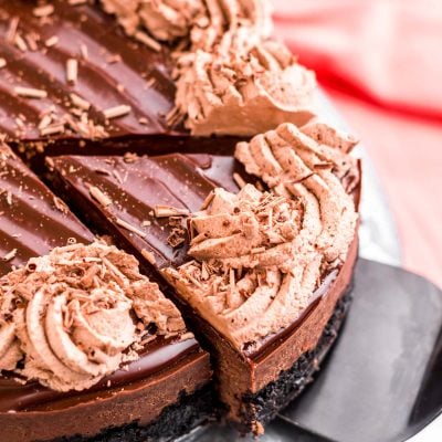 Close up photo of a slice of instant pot chocolate cheesecake being removed from the whole cake on a serving spatula.