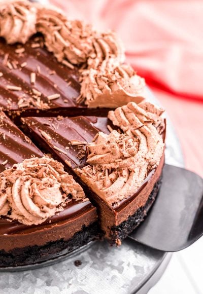 Close up photo of a slice of instant pot chocolate cheesecake being removed from the whole cake on a serving spatula.