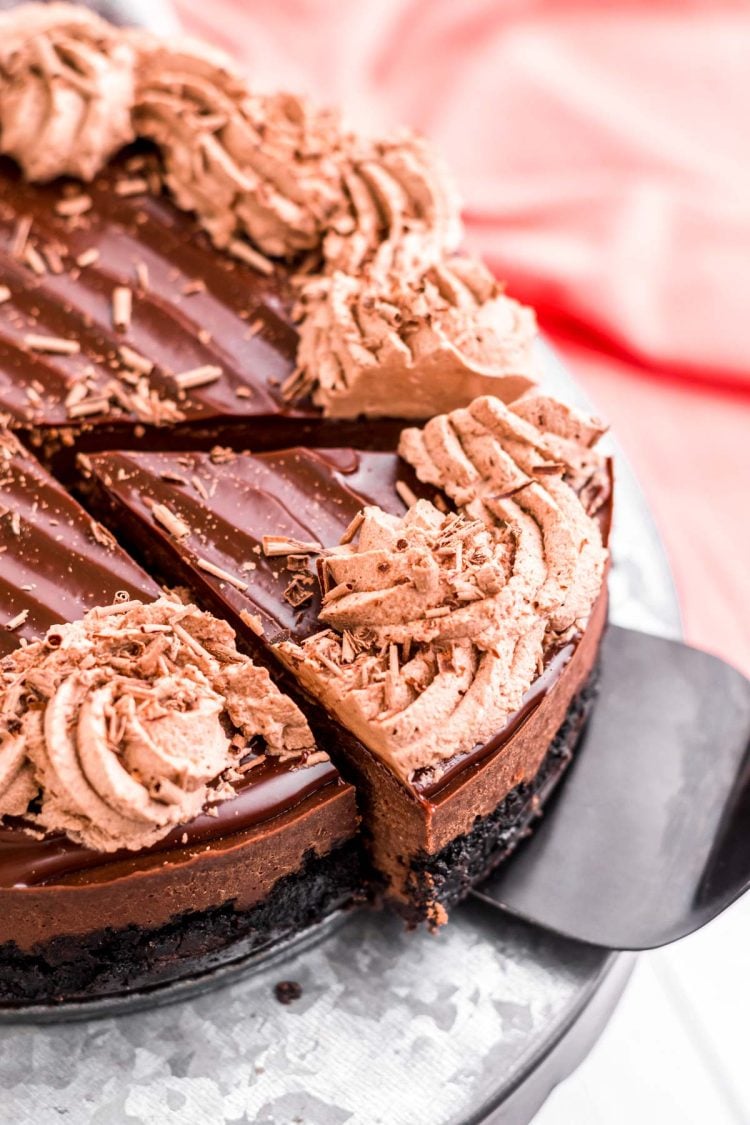 Close up photo of a slice of instant pot chocolate cheesecake being removed from the whole cake on a serving spatula.