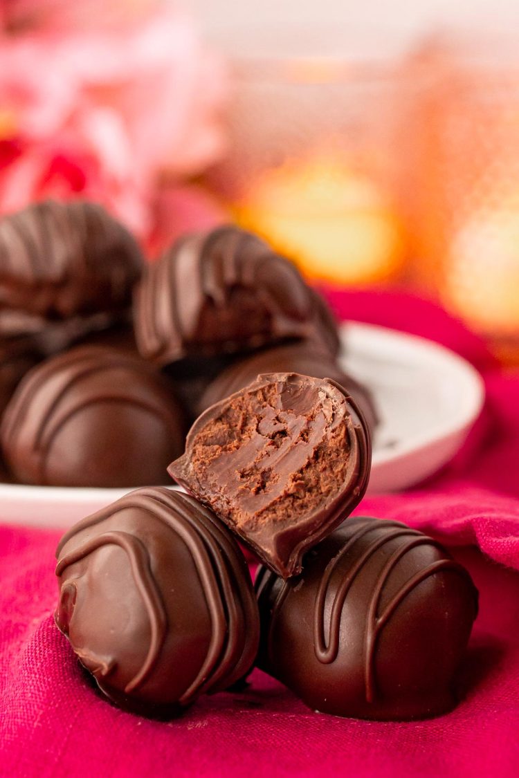 Close up photo of three chocolate truffles on a pink napkin with a bite taken out of the top one.