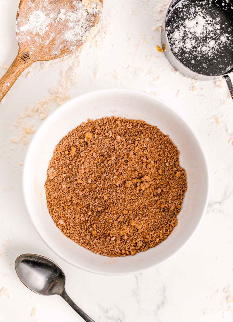 Brown sugar, cinnamon, and flour mixed together in a white bowl on a marble surface.