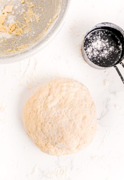 Bread dough in a ball on a floured marble surface.