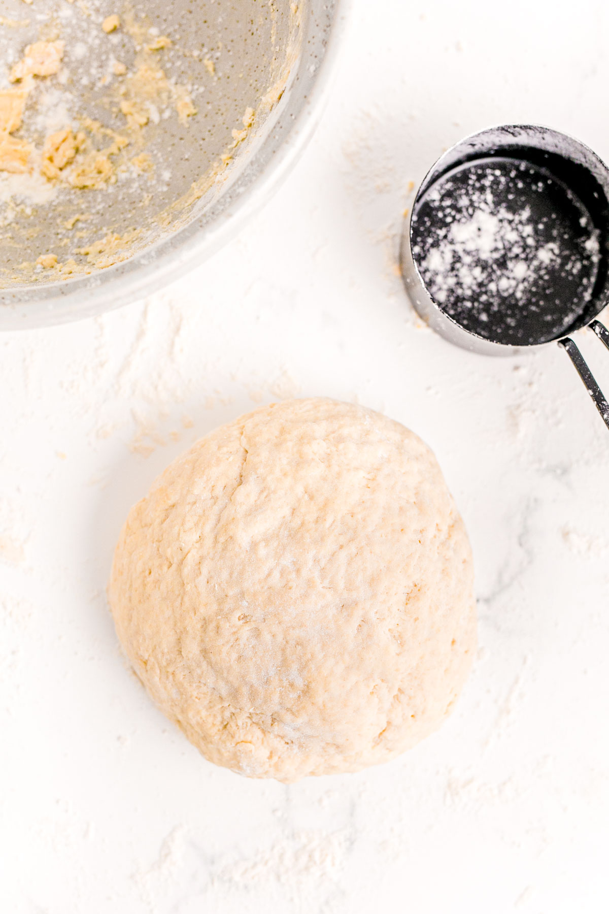 Bread dough in a ball on a floured marble surface.