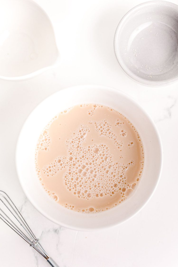 Overhead photo of yeast and water blooming in a white bowl.