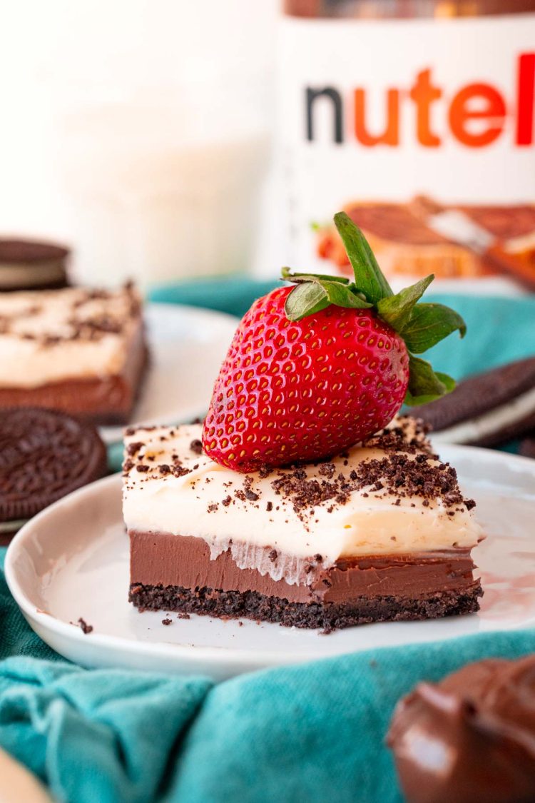 A nutella cheesecake bar on a small white plate with a bite taken out of it.