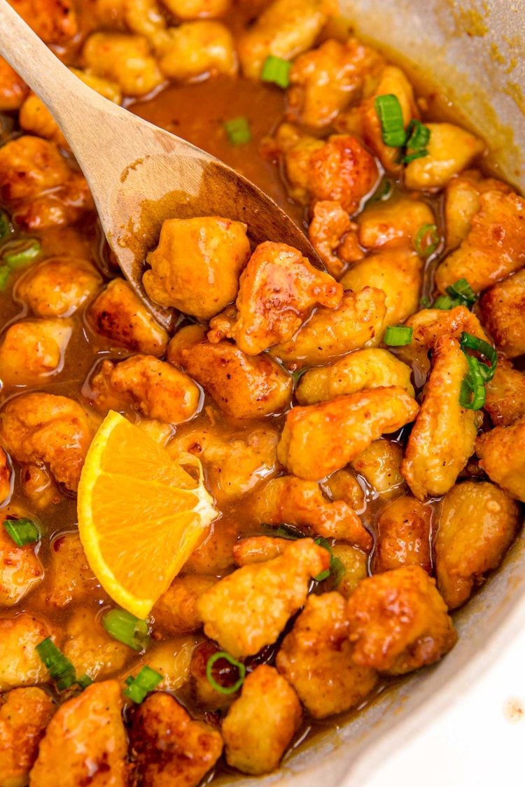 Close up photo of orange chicken being cooked in a skillet.