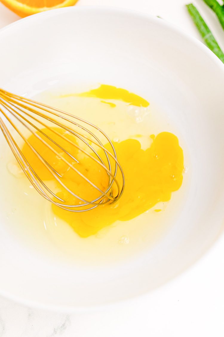 Eggs being beaten in a white bowl.