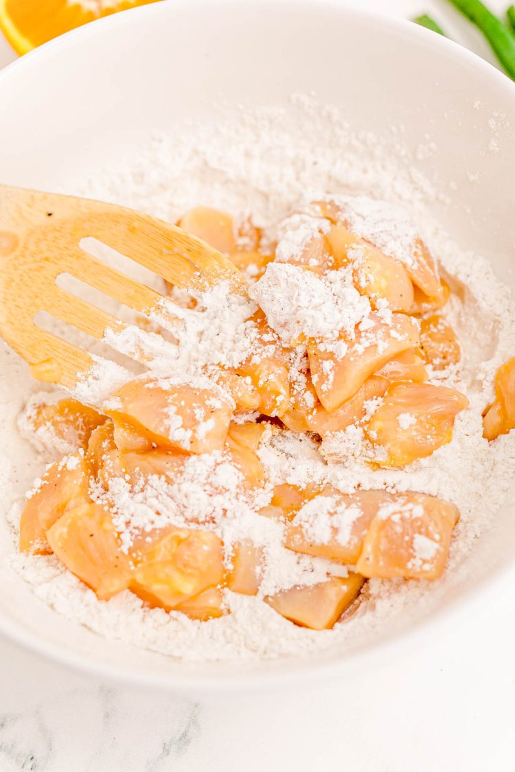 Chicken pieces being coated in flour.