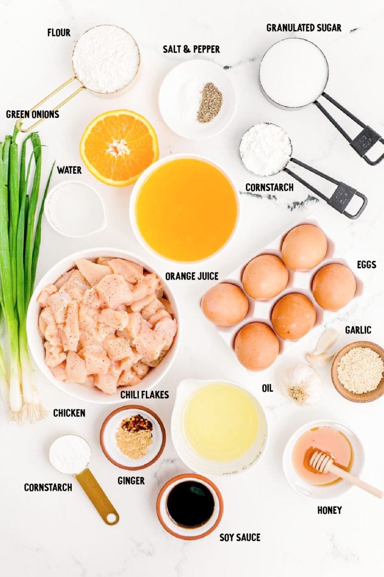 Overhead photo of ingredients to make orange chicken prepared on a marble counter.