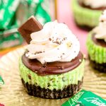 Close up photo of a mini chocolate mint cheesecake on a gold foil cupcake liner on a pink surface.