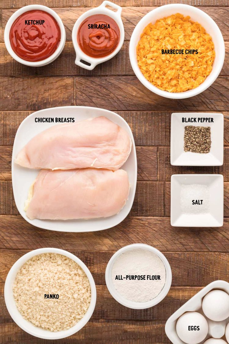 Ingredients to make potato chip breaded chicken tenders prepped on a wooden table.