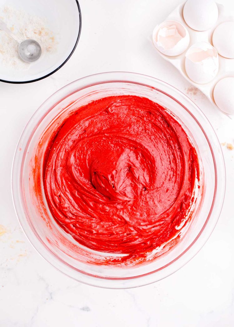 Red velvet cake batter in a glass mixing bowl.