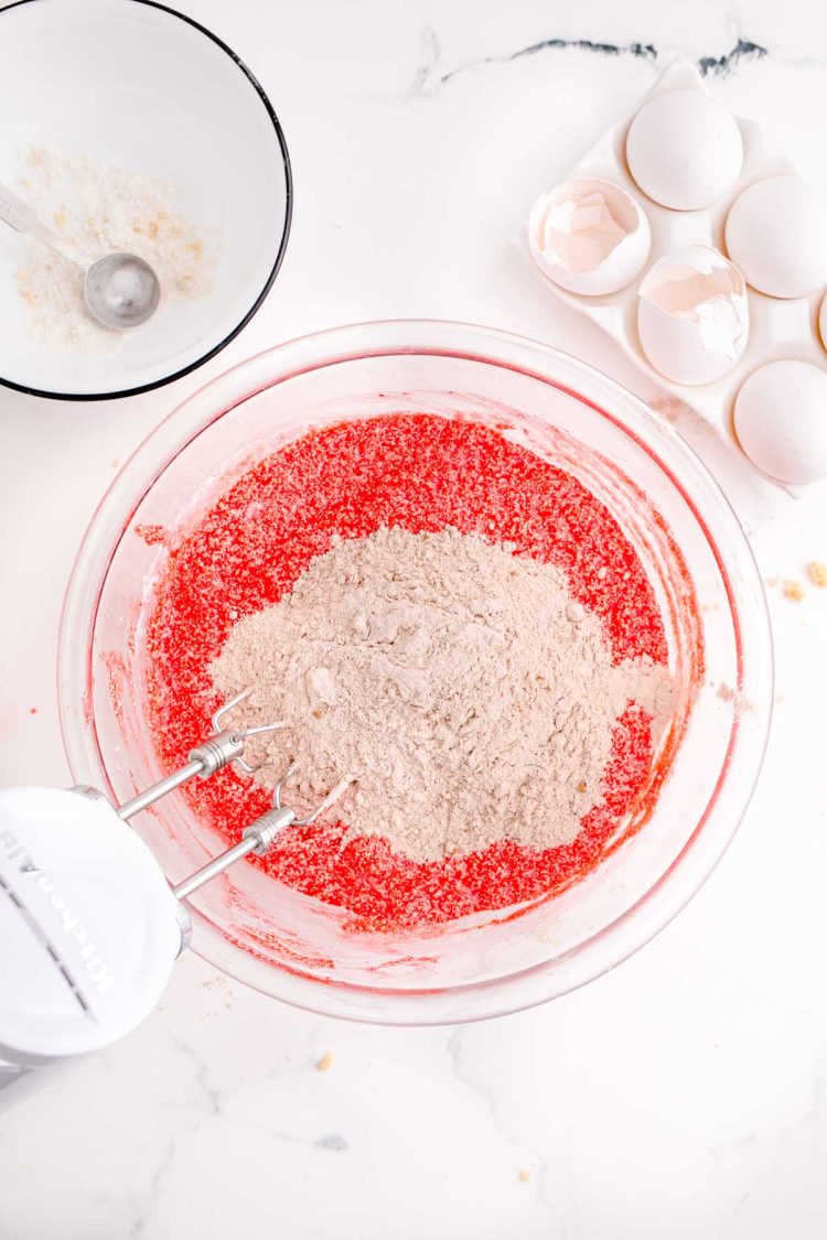 Red velvet cake batter being prepared in a glass mixing bowl to make whoopie pies.