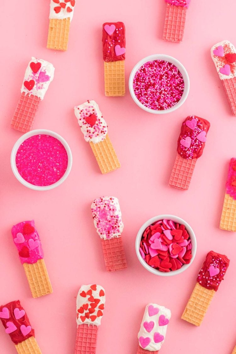 Overhead photo of Valentine's Day decorated sugar wafer cookies on a pink surface.