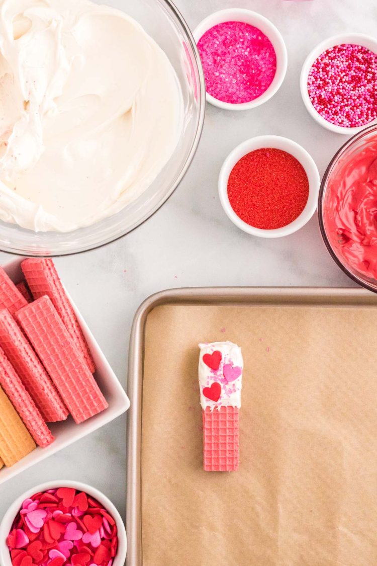 Ingredients on a marble counter making dipped sugar wafers decorated for Valentine's Day.